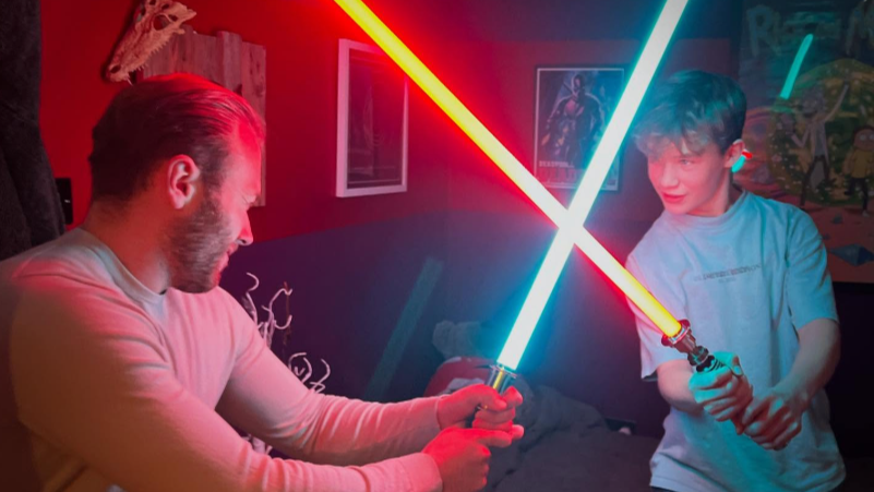 Two fans sparring with illuminated sabers